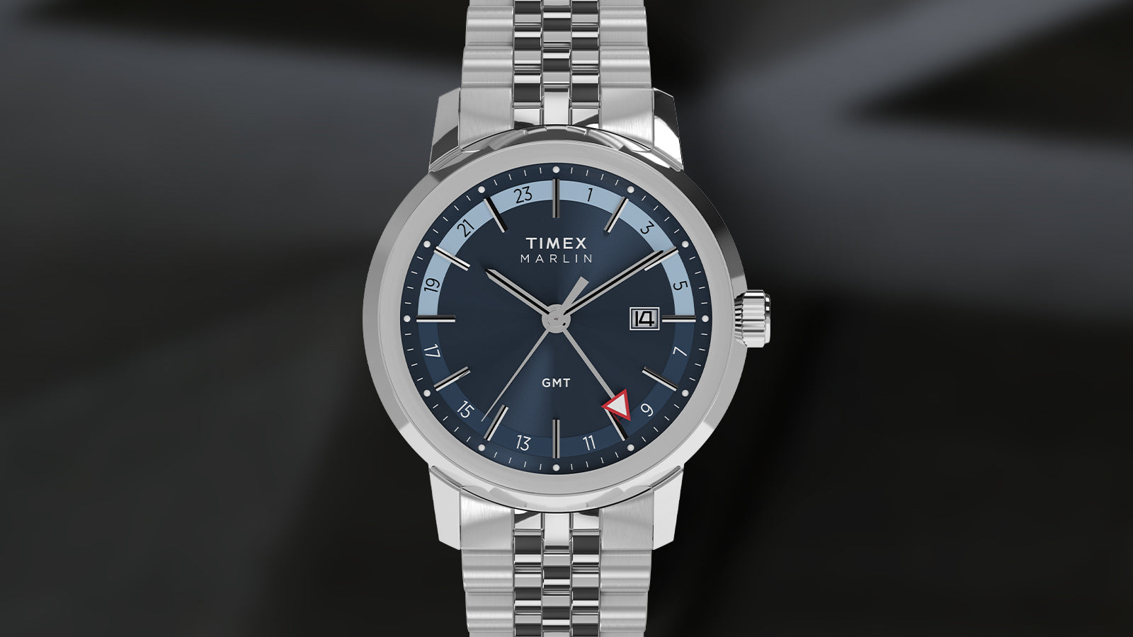 Front view of the Timex Marlin® Quartz GMT featuring a blue sunray dial, silver-tone hands and indices, a 24-hour scale, red-arrow GMT hand, and a date window at 3 o’clock, encased in polished stainless steel with a matching multi-link bracelet.
