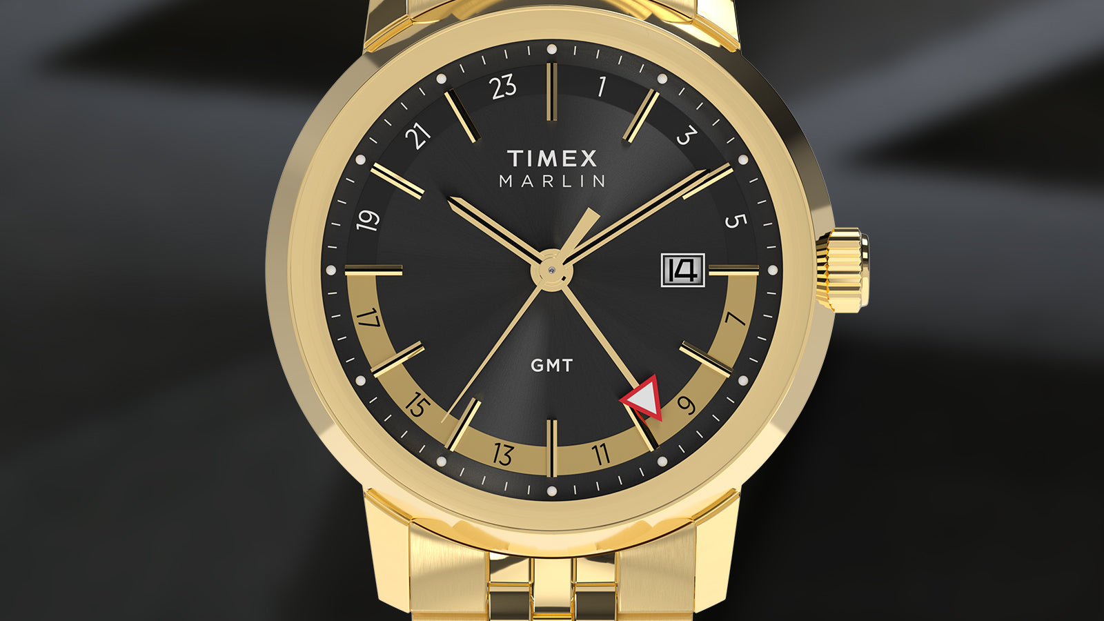 A front-facing render of the gold-tone Timex Marlin® Quartz GMT. The black sunray dial is highlighted by a two-tone 24-hour ring in gold and black, a white date window, and a red arrow GMT hand pointing to 9.