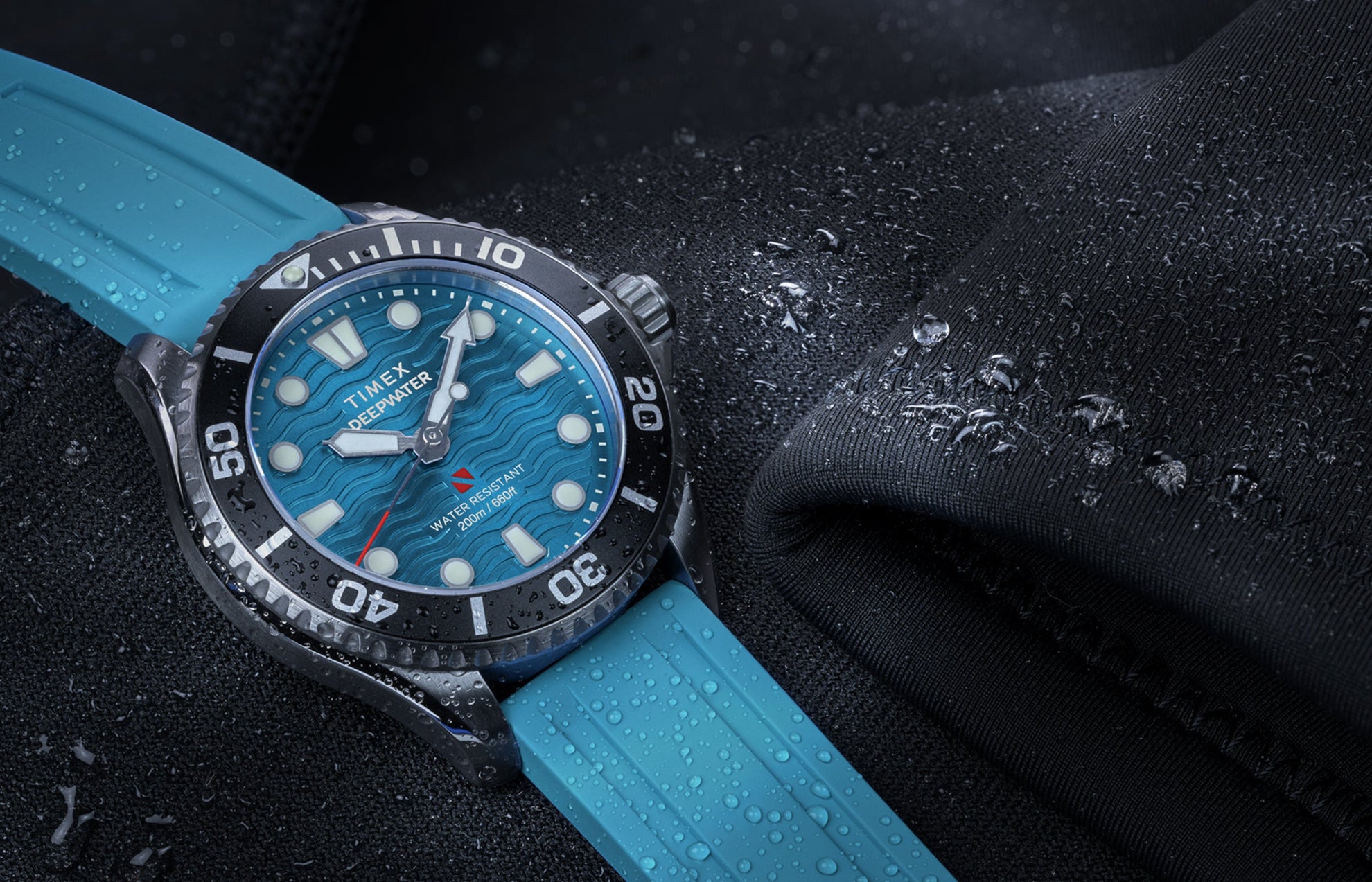 Timex Deepwater Meridian 200 dive watch with aqua blue strap and dial, resting on a wetsuit with water droplets.