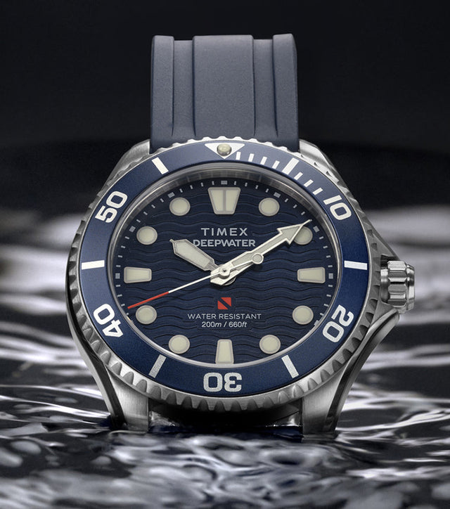 Timex Deepwater Meridian 200 with a blue strap and wave-pattern dial resting on the surface of dark water.