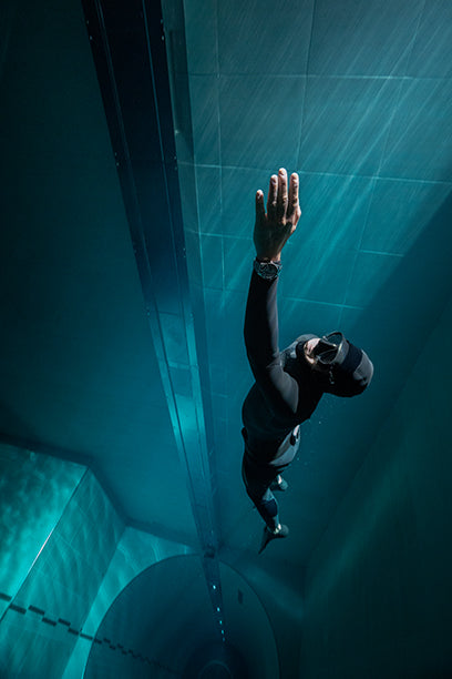 Freediver swimming vertically underwater wearing the Timex Deepwater Meridian 200 dive watch.
