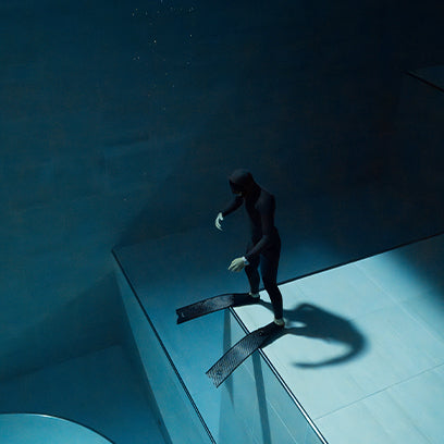 Diver standing underwater in full wetsuit and fins, with the Timex Deepwater Meridian 200 visible on the wrist.