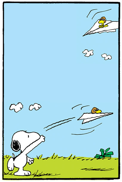 Snoopy stands on the grass, throwing two paper airplanes into the sky. Woodstock is riding one paper airplane, while another bird rides the other, with small clouds in the background.
