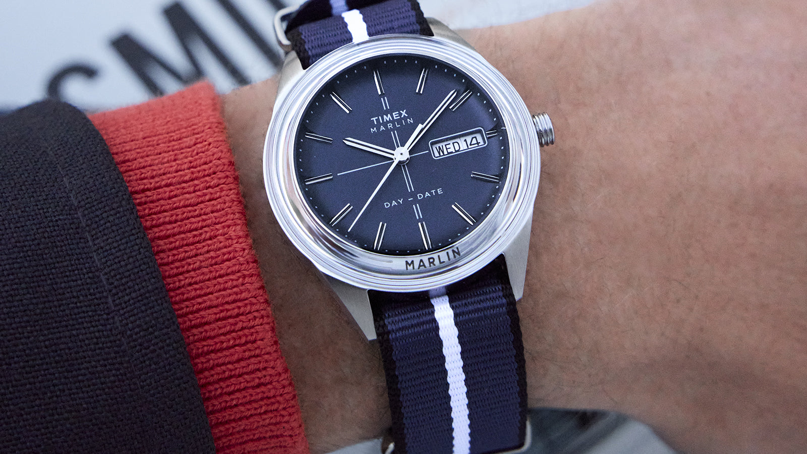 Timex Marlin® Jet Quartz watch worn on wrist, showing the sunray blue dial, slim silver-tone hands, and striped navy fabric strap.