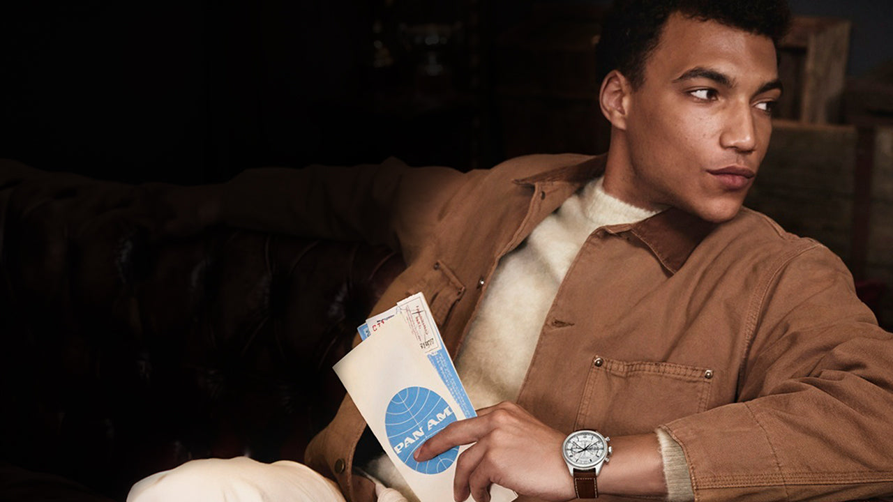 Model wearing the Timex x Pan Am® Waterbury Ace Chronograph while holding vintage Pan Am travel documents, evoking mid-century air travel style.