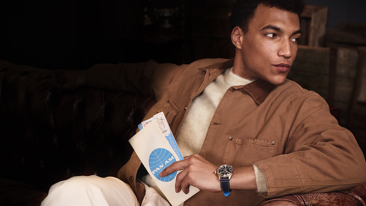 Model wearing the Timex x Pan Am® Waterbury Ace while holding vintage Pan Am travel documents, evoking mid-century air travel style.