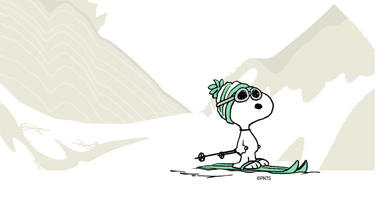 Illustration of Snoopy wearing ski goggles and a green beanie, standing on skis with poles against a snowy mountain backdrop.