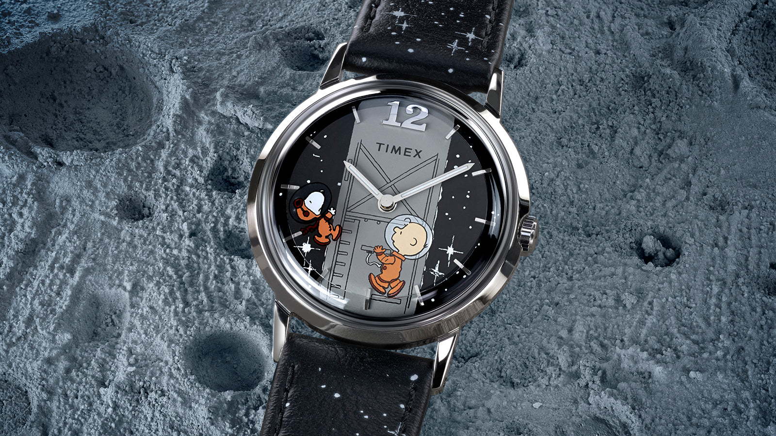 Detailed view of the Timex x Peanuts® Marlin® Hand-Wound watch resting on a lunar surface background. The dial artwork depicts Charlie Brown and Snoopy in space suits with white stars scattered across the black dial and strap.