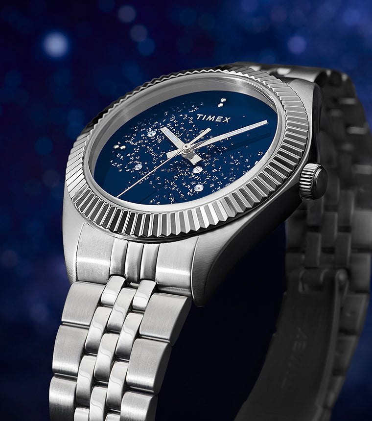 Timex Legacy watch with a stainless-steel case and bracelet featuring a deep blue dial with sparkling crystal accents that resemble a starry night sky.