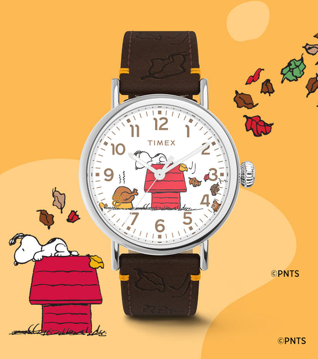 Timex x Peanuts® Standard Thanksgiving Edition watch displayed next to a Snoopy and Woodstock illustration surrounded by colorful falling leaves, celebrating a cozy fall theme.