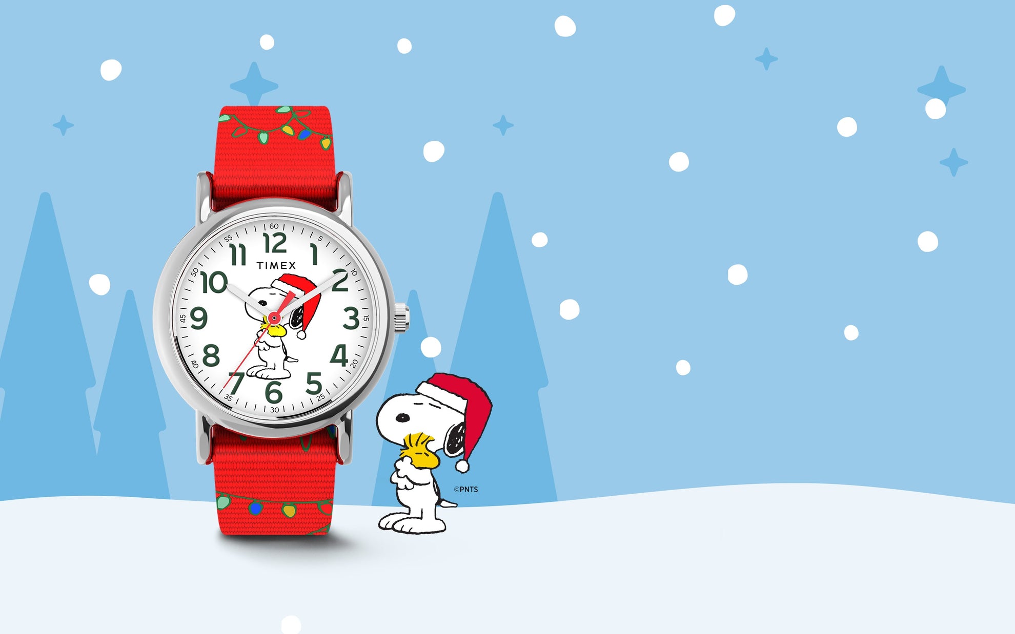 Timex x Peanuts® Weekender Snoopy Santa Hat watch featuring Snoopy in a Santa hat holding Woodstock on a white dial with green numerals. The watch has a red fabric strap decorated with holiday string lights, set against a snowy winter background with Snoopy and Woodstock illustration.