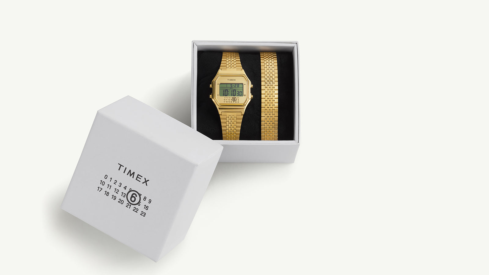 Overhead view of the Timex x MM6 T80 watch inside its branded MM6 x Timex packaging, showcasing the full set presentation with bracelet and box.