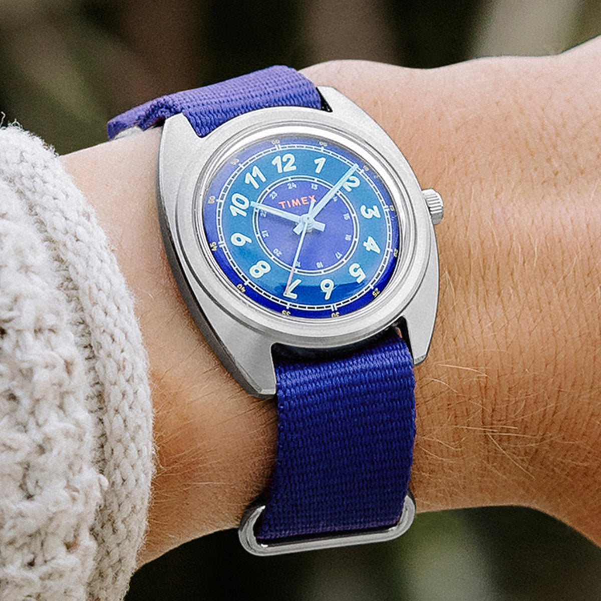 A close-up of the Timex x Worn & Wound Whirlpool watch on a person’s wrist, showing the vibrant blue dial and blue strap paired with a textured knit sweater.