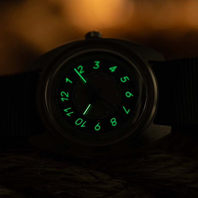The Timex x Worn & Wound Storm watch in low light, with its numerals and hands glowing bright green against the darkened dial.