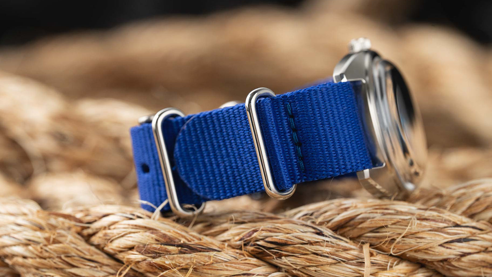 A close-up of the blue strap on the Timex x Worn & Wound Whirlpool, showing the stitching and polished hardware resting on coiled rope.