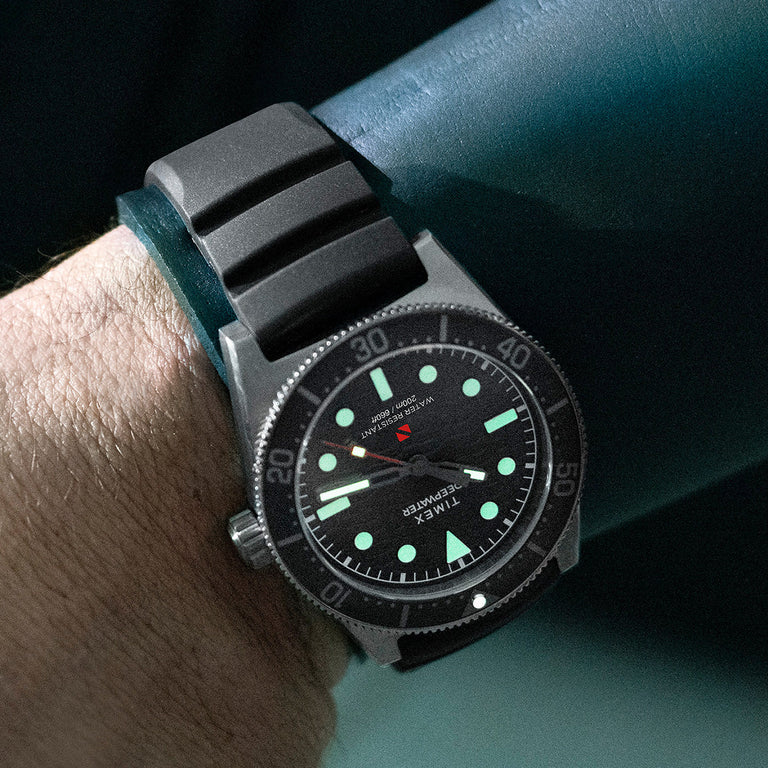 Diver’s wrist wearing the Timex Deepwater Reef 200 underwater, showing the watch’s luminous dial and durable construction designed for deep-sea exploration.