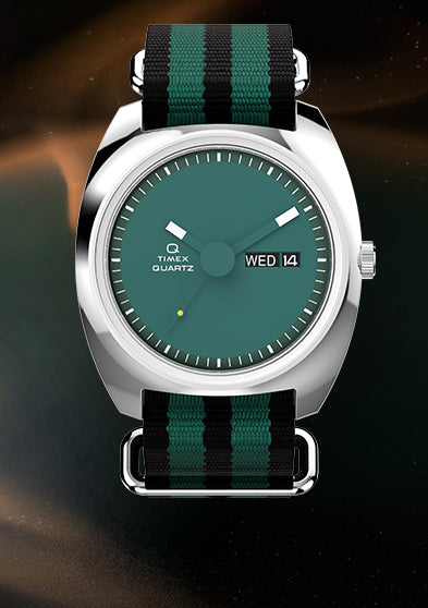 Full product image of the Q Timex® 1975 Enigma watch with teal dial and striped nylon strap centered against an abstract dark cosmic background, highlighting its 1970s-inspired design.