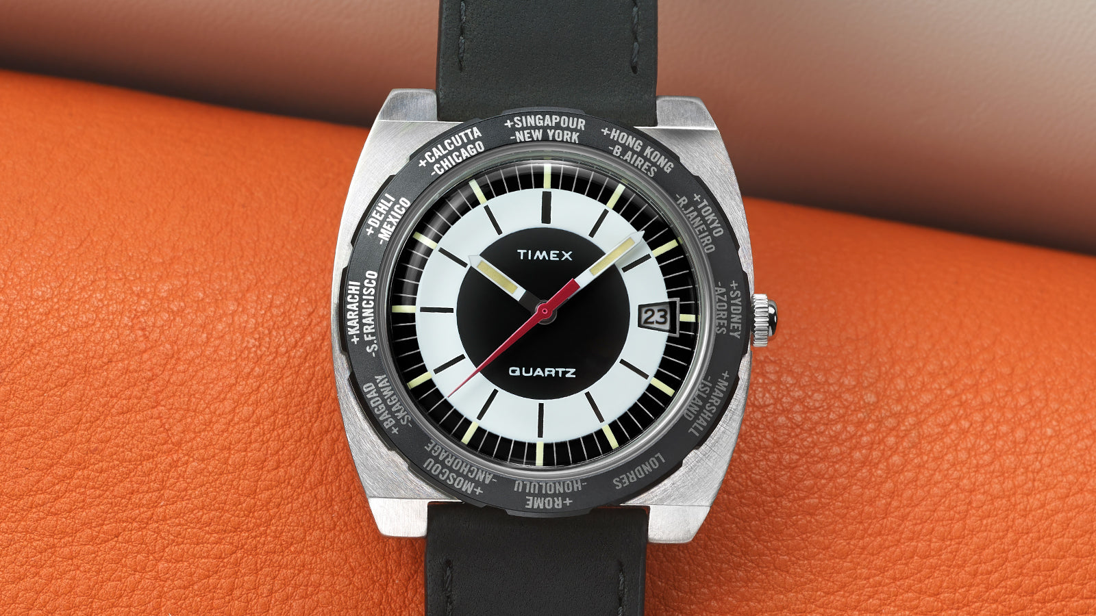 Front-facing shot of the Timex World Time Reissue watch showing the full dial with bold black-and-white design, red seconds hand, yellow-tipped hour and minute hands, and date window at 3 o’clock.