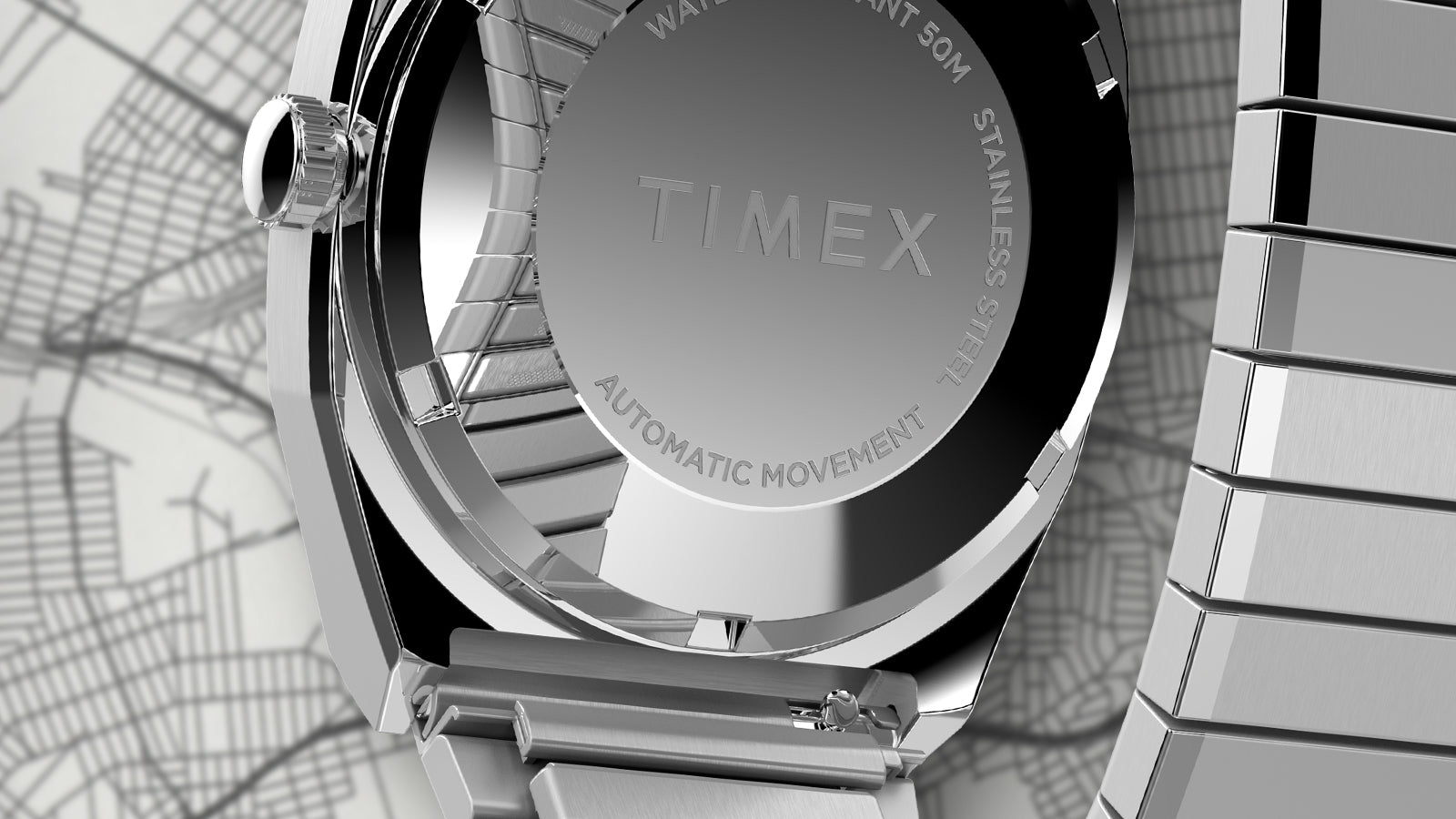 Macro view of the caseback of the Timex® Automatic 1983 E Line Reissue showing the engraved TIMEX logo, automatic movement marking, and stainless-steel case with brushed finishing.