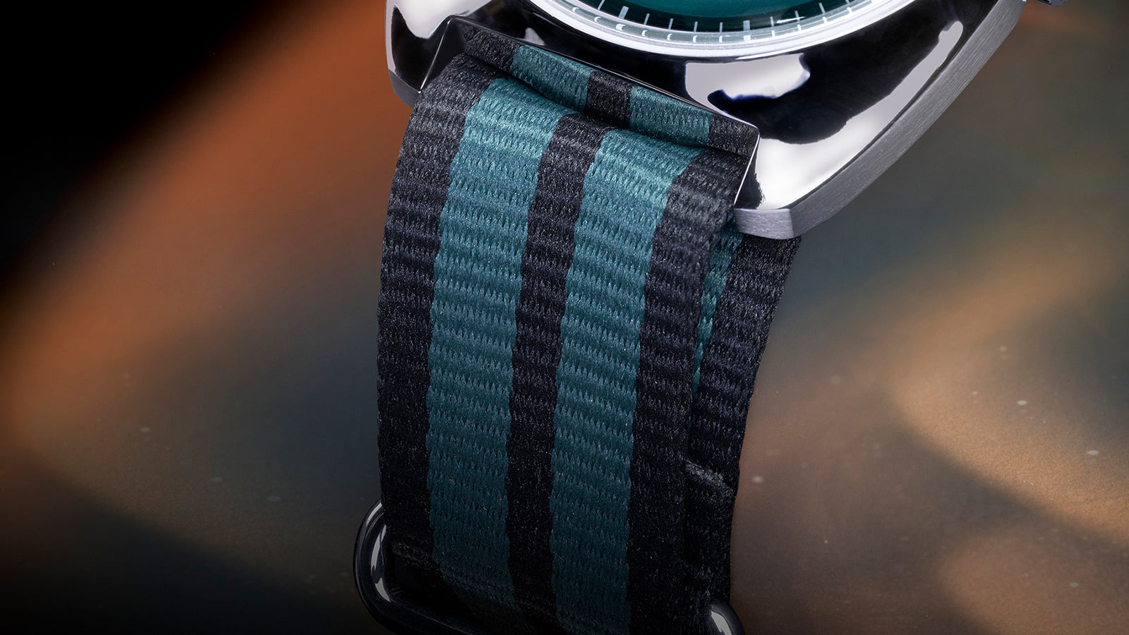 Macro shot of the Q Timex® 1975 Enigma fabric strap showing its black and green striped pattern, texture, and sturdy loop-through attachment.