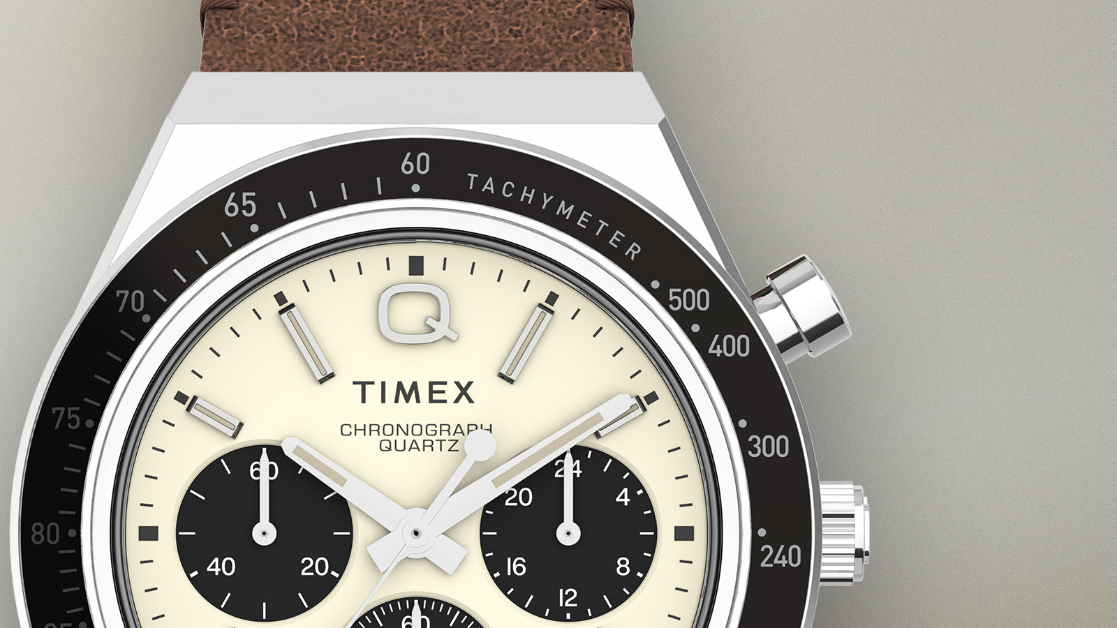 Detailed close-up of the Q Timex Chronograph dial showing the cream face, black sub-dials, tachymeter scale, and chrome pushers.