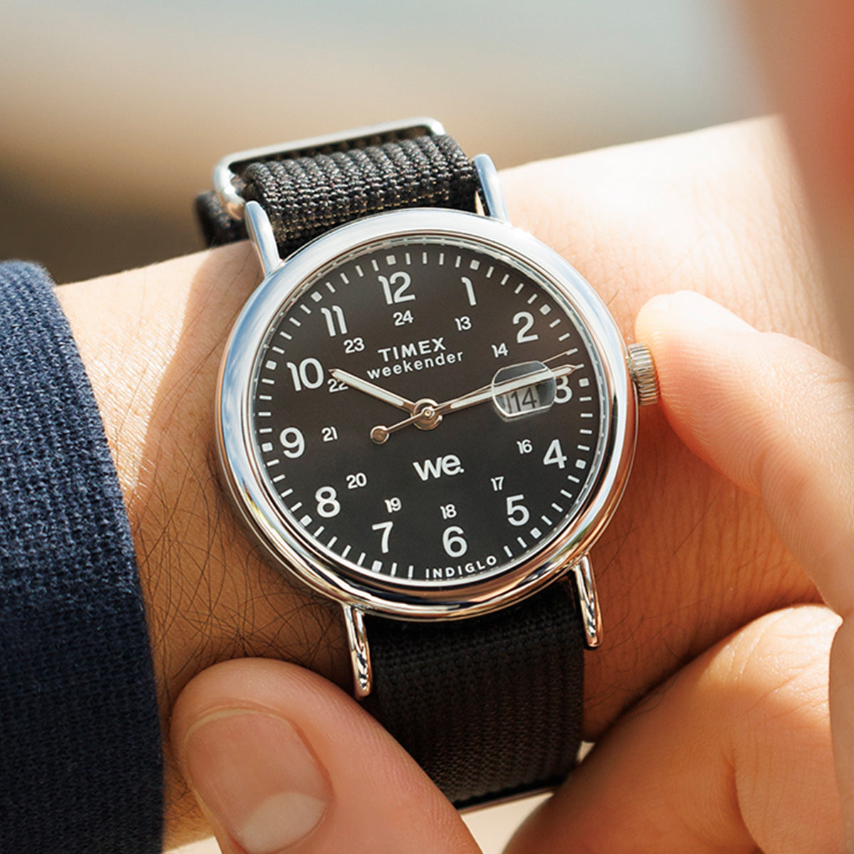 Detailed wrist shot of the Timex Weekender with black dial and black strap as the crown is adjusted outdoors.