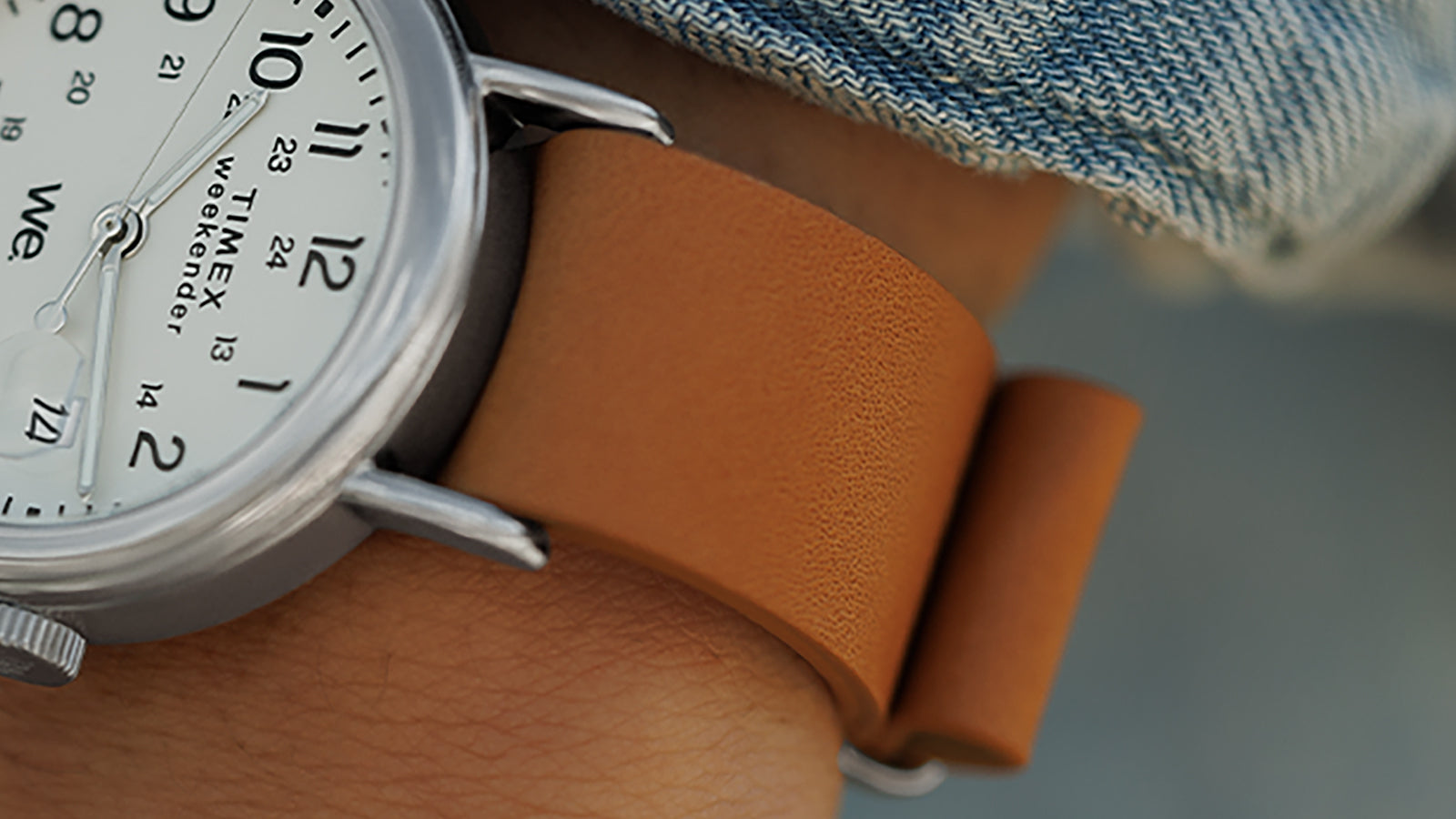 Close-up detail of the tan leather strap and silver-tone case of the Timex Weekender on wrist.
