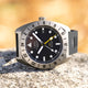 Front view of the Timex Expedition North GMT Titanium Automatic highlighting the matte black dial, white luminous markers, yellow GMT hand, and date window at 3 o’clock.