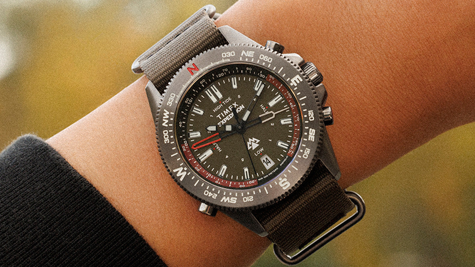 Timex Expedition Tide-Temp-Compass worn on wrist, highlighting its bold compass bezel, luminous dial, and green strap with brushed hardware.