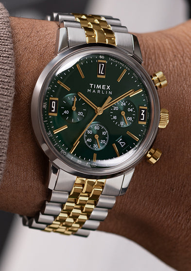 Person wearing Timex Marlin Chronograph Tachymeter with green dial and two-tone bracelet, styled with a taupe sweater sleeve.
