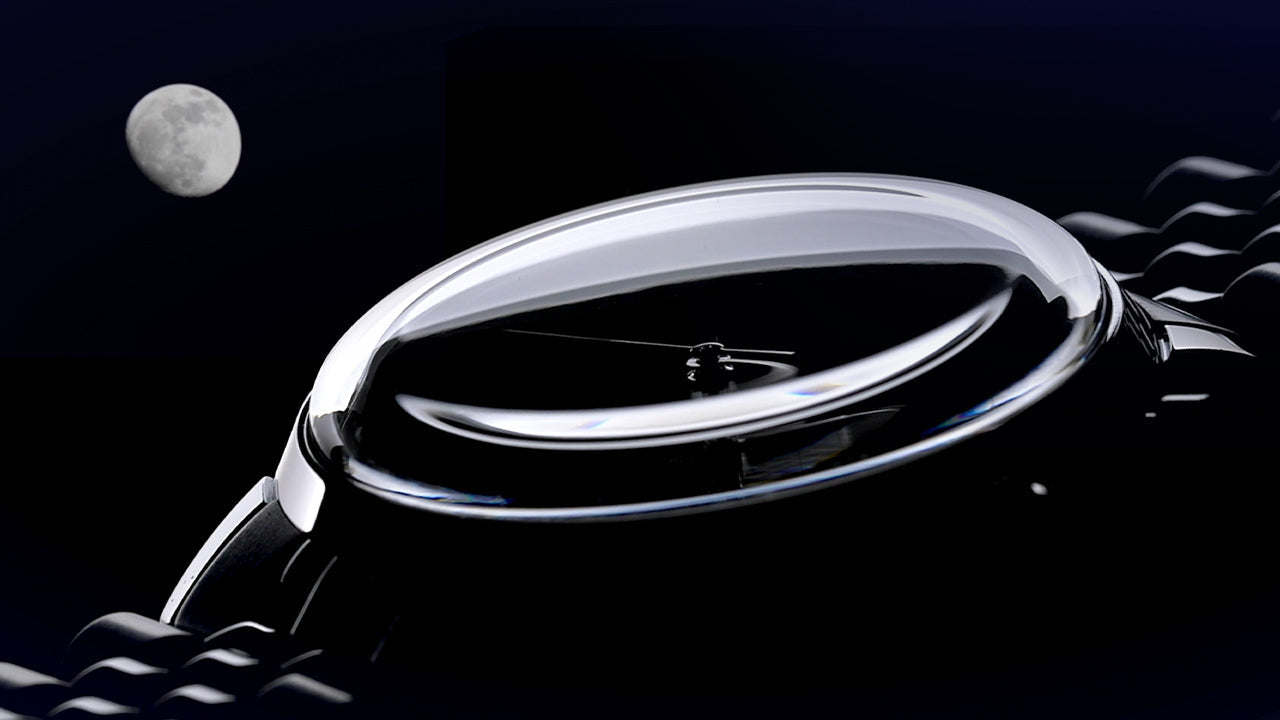 Close-up of the Timex Marlin Moon Phase Multifunction showing domed crystal and moonlit reflection against a night sky background with a visible moon.