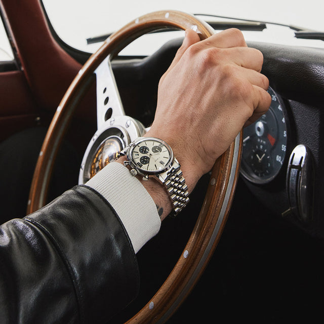 Close-up of man driving a vintage car wearing the Timex Marlin Chronograph Tachymeter with silver dial and stainless-steel bracelet.