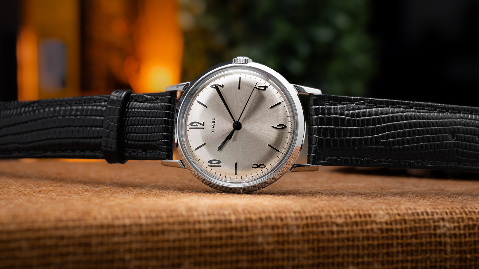 Front view of Timex Marlin Hand-Wound watch showing its minimalist silver dial, Arabic numerals at 12, 2, 4, 6, 8, and 10, and textured black leather strap.