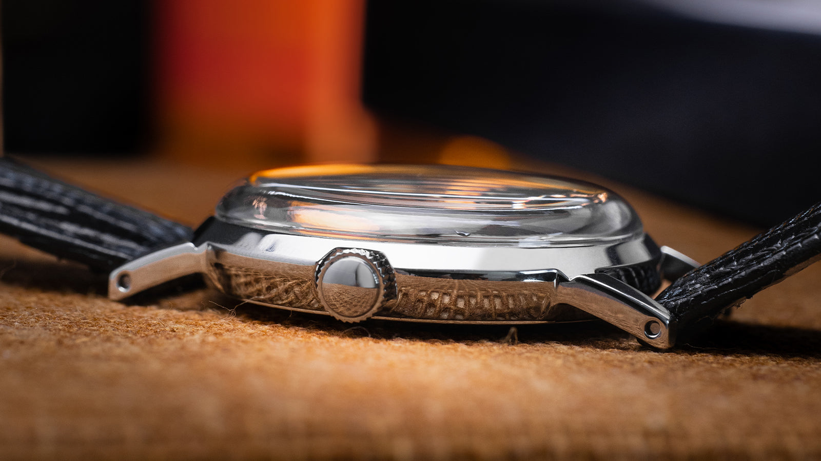 Side profile of Timex Marlin Hand-Wound watch showing its domed acrylic crystal, polished case, and slender lugs on a black textured leather strap.