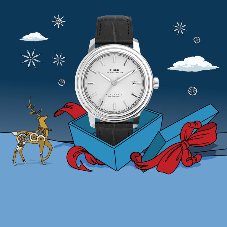 A Timex Waterbury Automatic watch with a polished stainless steel case, silver dial, and black leather strap. The dial features simple hour markers, a date window at 3 o’clock, and “Established in 1854” text along the edge.