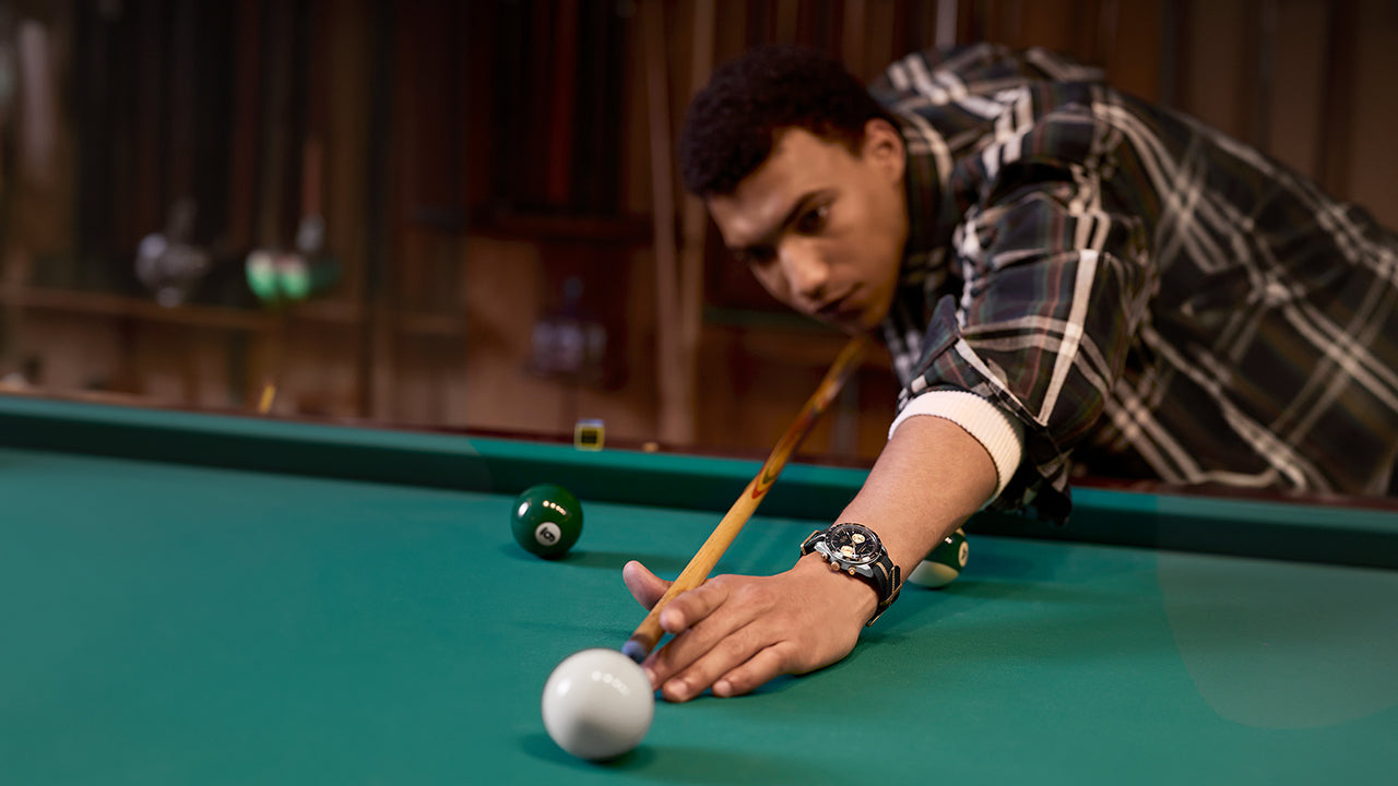 Man wearing the Timex Waterbury Heritage Chronograph taking a pool shot, showcasing the watch’s sporty and refined design.