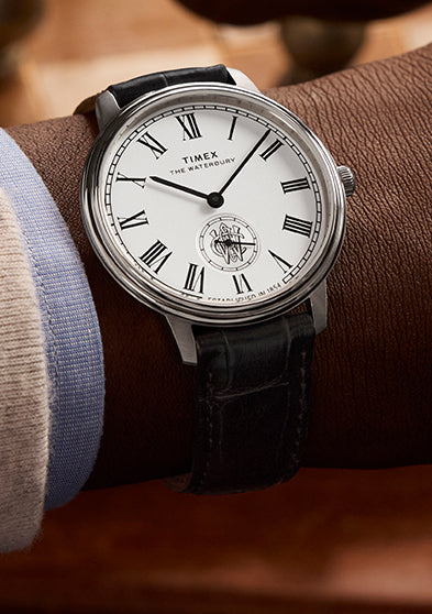 Timex Waterbury Metropolitan Sub-Second watch on wrist, displaying classic white dial and black leather strap during a chess game.