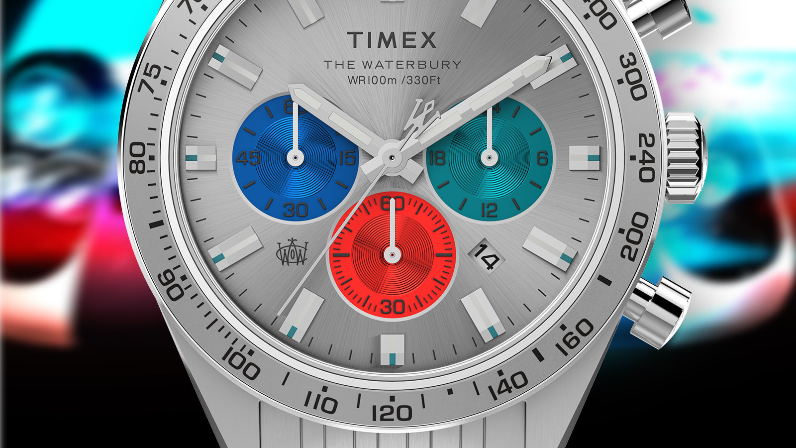 Close-up of the Timex Waterbury Chronograph dial displaying the three-color sub-dials, brushed silver texture, and tachymeter scale with colorful abstract background.