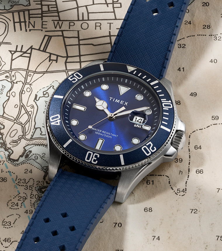 Timex Harborside Coast watch with a blue dial and bezel, featuring a textured blue strap, placed on a nautical map of Newport.