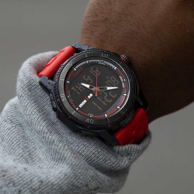 TIMEX® IRONMAN® Adrenaline Ana-Digi watch with red strap worn on wrist, showing analog-digital display and black bezel with red markings.