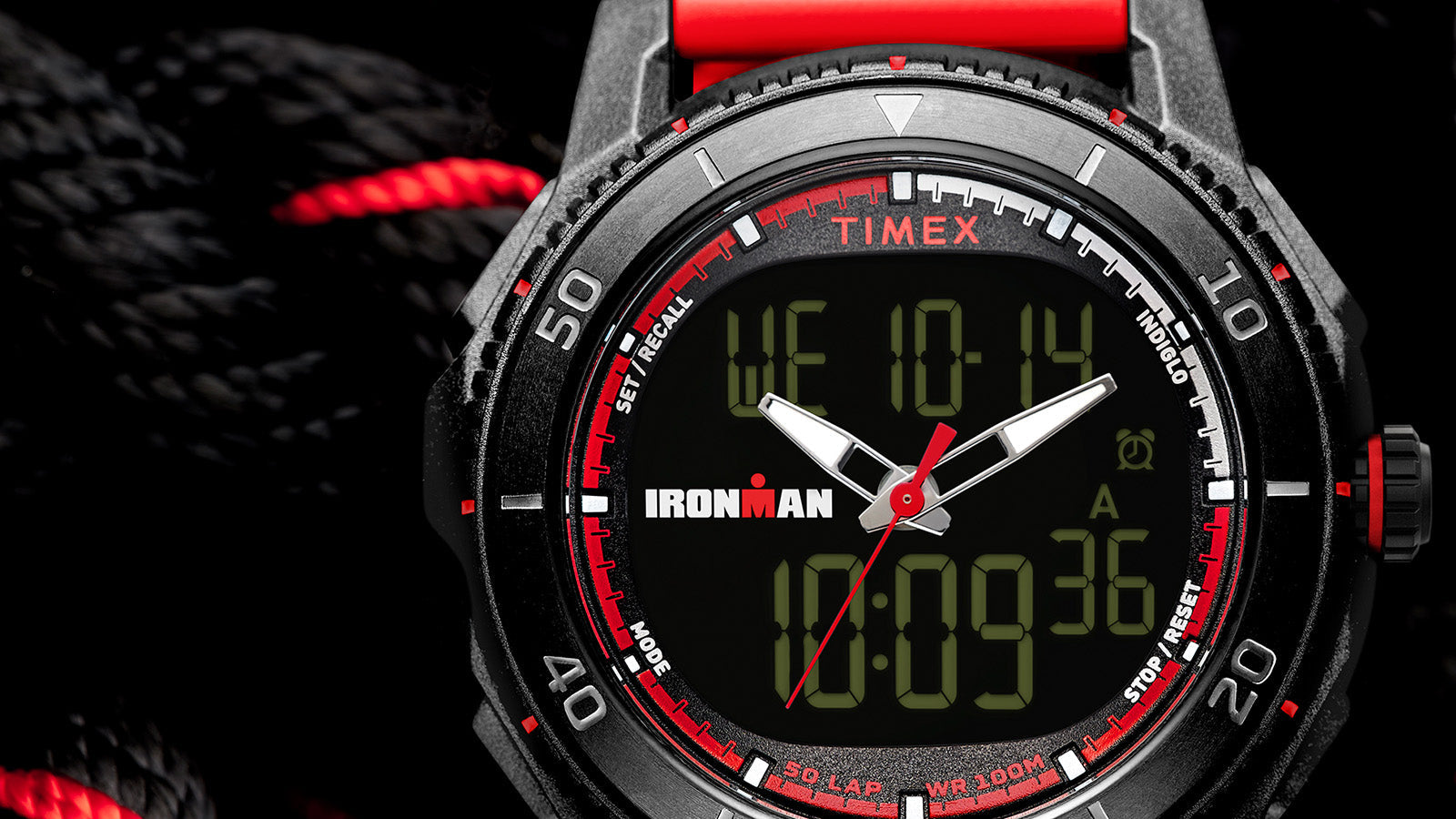 TIMEX® IRONMAN® Adrenaline Ana-Digi watch with black case, red accents, and red resin strap displayed on coiled black rope with red details.