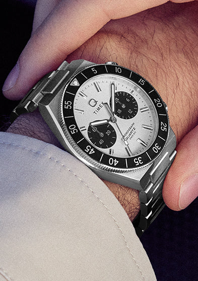 Close-up of the Q Timex Continental Chronograph on the wrist highlighting the stainless steel case, black bezel, and chronograph pushers.