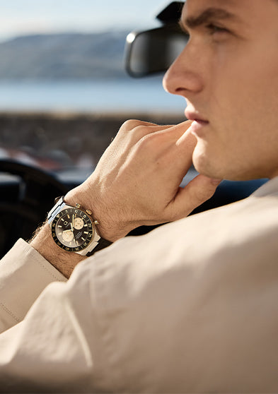 Q Timex® Continental Chronograph worn on wrist inside a vintage car, highlighting the black and champagne dial and leather strap.