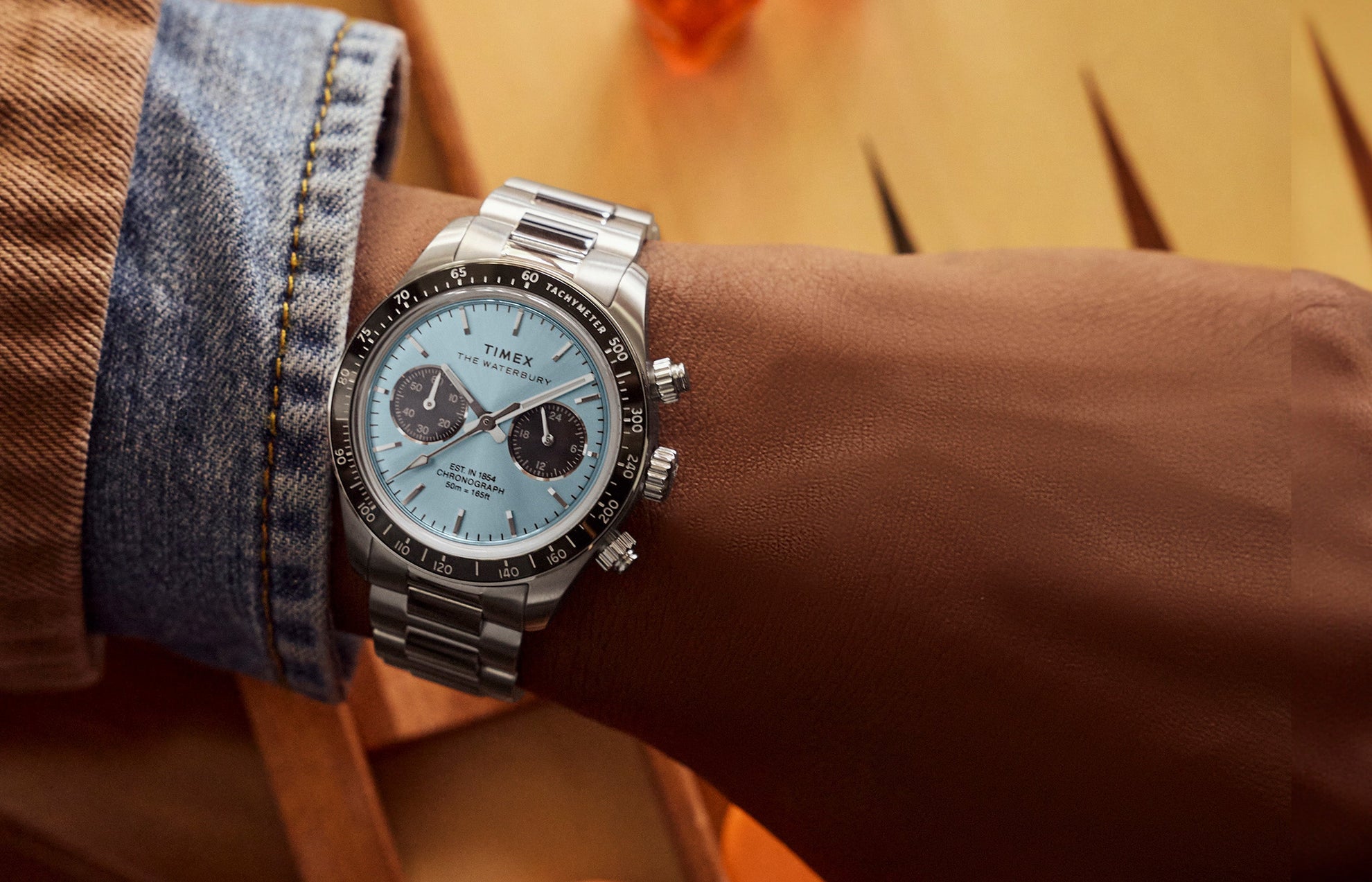 Timex Waterbury Heritage Chronograph worn on wrist, featuring a stainless steel bracelet, light blue dial, and black tachymeter bezel.