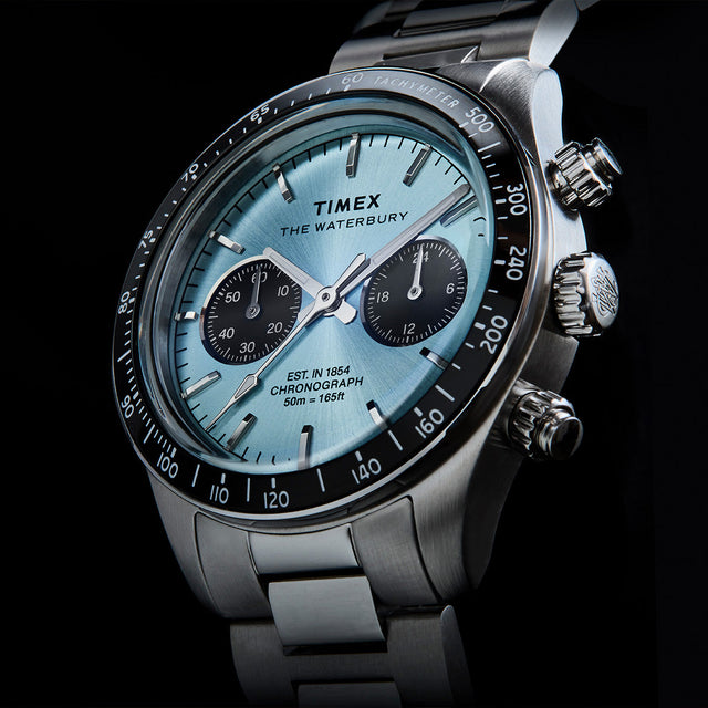 Angled close-up of Timex Waterbury Heritage Chronograph showing the light blue dial, chronograph subdials, and tachymeter bezel.