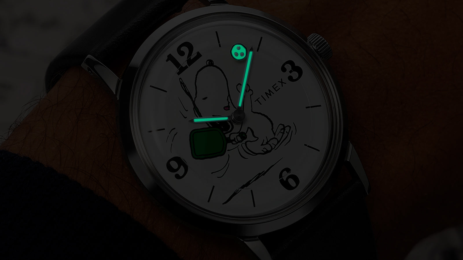 Peanuts® x Timex Marlin® Pickleball watch illuminated with INDIGLO® backlight, showing glowing hands and pickleball detail on dial.
