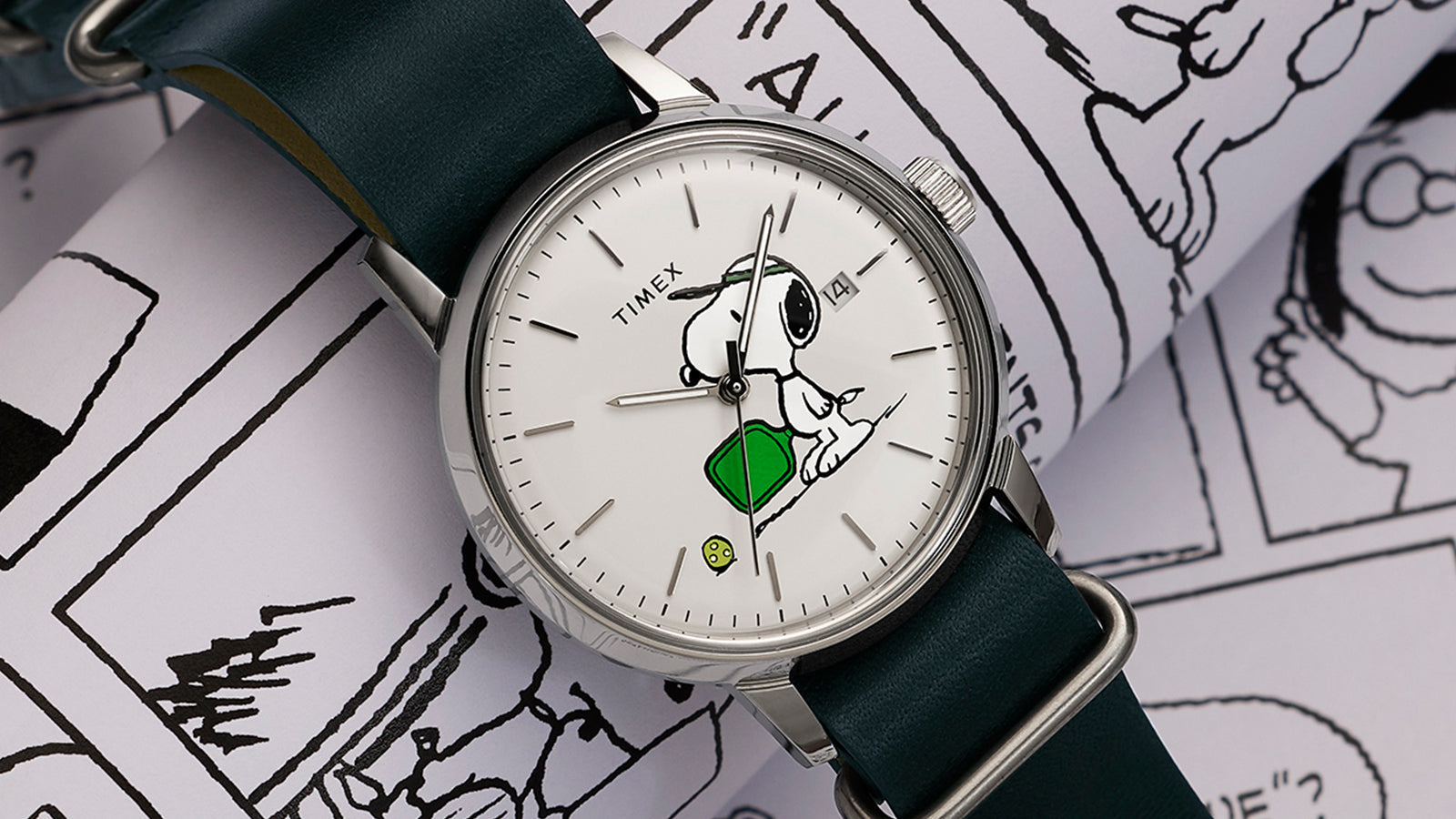 Peanuts® x Timex Marlin® Automatic Pickleball watch with Snoopy pickleball dial and green leather strap displayed on Peanuts comic strip background.