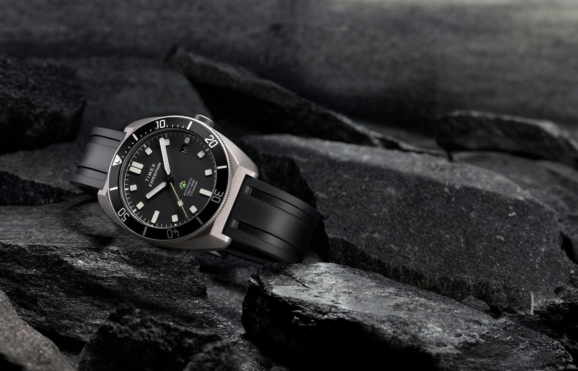 Timex Expedition Pioneer Titanium Automatic watch with black dial and rubber strap placed on rugged rocks