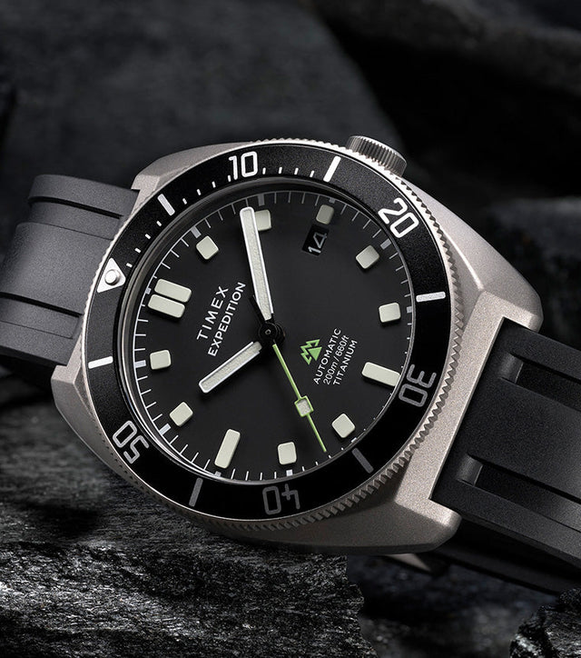 Timex Expedition Pioneer Titanium Automatic watch with black dial and rubber strap placed on rugged rocks