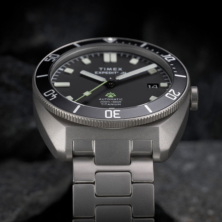 Angled close-up of the Expedition® Pioneer Titanium Automatic showcasing the matte titanium case, bold luminous markers, and “Automatic 200m/660ft Titanium” text.